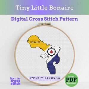 May include: A cross-stitch pattern of Bonaire, featuring the island's shape in yellow, blue, and white, framed in a wooden hoop. The text "Tiny Little Bonaire" and "Digital Cross Stitch Pattern" are displayed above the design. The pattern measures 2.9" x 3.5".