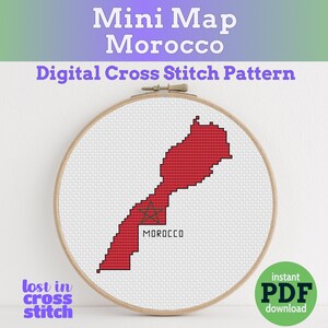 以下が含まれることがあります： 木製の刺繍枠に表示された、赤色のモロッコ地図のクロスステッチパターン。「Mini Map Morocco」と「Digital Cross Stitch Pattern」の文字が上部にあります。「lost in cross stitch」と「MOROCCO」の文字も表示されています。