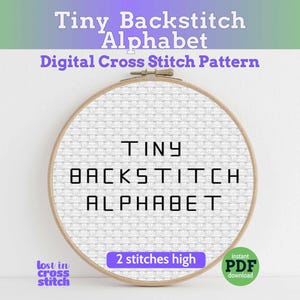 Könnte beinhalten: Ein runder Stickrahmen aus Holz mit weißem Aida-Stoff, auf dem der schwarze Text TINY BACKSTITCH ALPHABET gestickt ist. Das Bild enthält den Text Tiny Backstitch Alphabet, Digital Cross Stitch Pattern, 2 stitches high und PDF.
