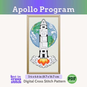 May include: A cross-stitch pattern featuring a rocket ship launching into space, with the word "APOLLO" vertically displayed. The design includes a backdrop of Earth and flames. The framed artwork measures 3.4 x 6.6 inches.