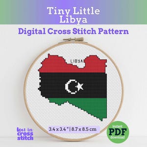 May include: A cross-stitch pattern of the Libyan flag in a wooden embroidery hoop. The design features the flag's red, black, and green colors, with a white crescent and star. The pattern is 3.4 x 3.4 inches (8.7 x 8.5 cm). Text reads "Tiny Little Libya" and "Digital Cross Stitch Pattern."