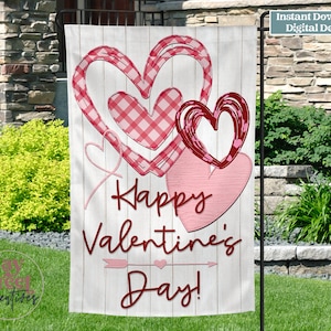 Könnte beinhalten: Eine weiße Gartenflagge mit einem roten und rosafarbenen Herzdesign. Die Flagge zeigt den Text "Happy Valentine's Day!" in roten Buchstaben.