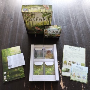 May include: A board game called Mischwald, with a green box, a set of cards, and instructions. The box features a forest scene with a fox.