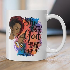 May include: White ceramic mug with a colorful watercolor background featuring a black woman with red hair praying. The mug has the text "She who kneels before God can stand before anyone Romans 8:31" printed on it.