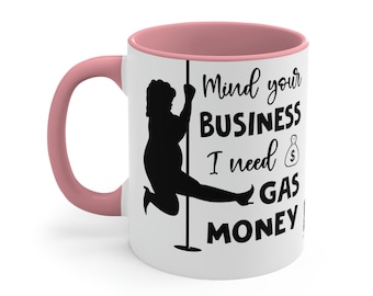May include: White ceramic mug with a pink interior and handle. The mug features a black silhouette of a person pole dancing, with the text "Mind your BUSINESS I need GAS MONEY".