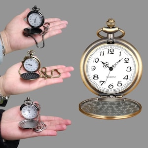 May include: Three open pocket watches with chains, in black, bronze, and silver tones, are displayed. The watches have white faces with black numerals and hands. The bronze watch is open, revealing an intricate pattern on the inside cover. The word "QUARTZ" is printed on the watch face.