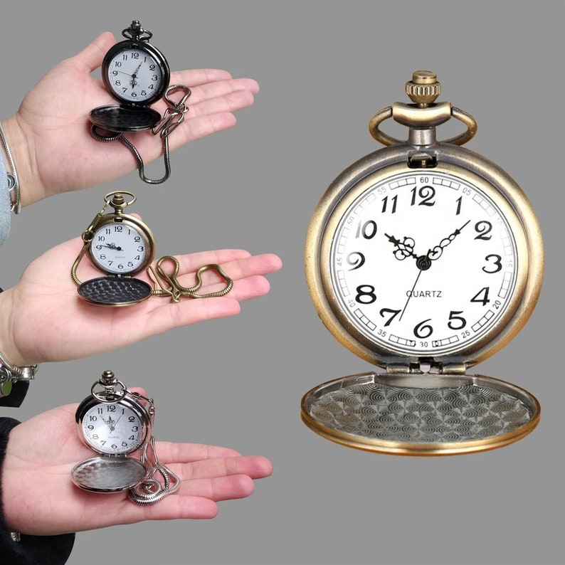 May include: Three open pocket watches with chains, in black, bronze, and silver tones, are displayed. The watches have white faces with black numerals and hands. The bronze watch is open, revealing an intricate pattern on the inside cover. The word "QUARTZ" is printed on the watch face.
