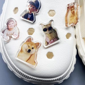 May include: White shoe with various colorful cartoon and animal character stickers. The stickers include a cartoon boy, a baby, a dog, and two cats.