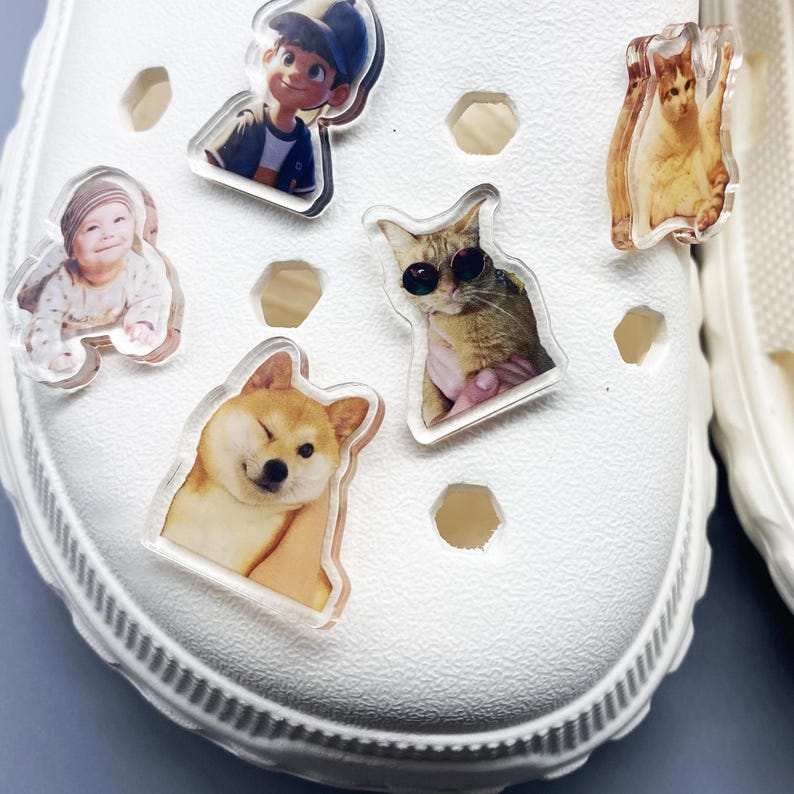 May include: White shoe with various colorful cartoon and animal character stickers. The stickers include a cartoon boy, a baby, a dog, and two cats.