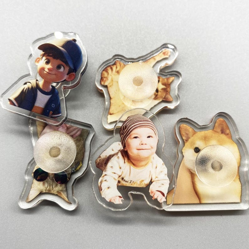 May include: Five clear acrylic photo charms with different images. The charms feature a boy in a baseball cap, a baby in a white shirt, a cat, a dog, and a cat wearing sunglasses.