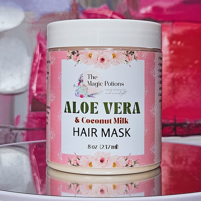 May include: A white jar with a pink label that says "The Magic Potions" and "Aloe Vera & Coconut Milk Hair Mask" with a floral design. The jar contains a white hair mask and is 8 oz (237 ml).