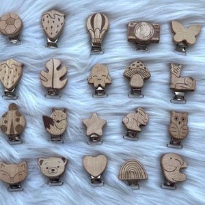Può includere: Un set di 16 morsi per bambini in legno con vari disegni, tra cui una coccinella, una volpe, una stella, un cuore, un arcobaleno, un gufo, un fungo, una mongolfiera, una macchina fotografica, una farfalla, una foglia, una fragola, un pallone da calcio, un lama, un coniglio e un gatto. I morsi sono tutti attaccati a clip argentate.