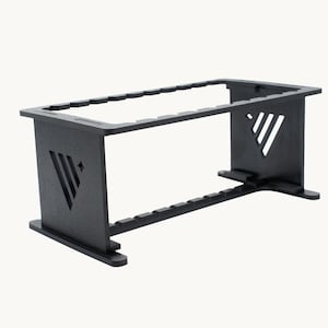 May include: A black display stand, rectangular in shape, with a geometric design. It features slots along the top and bottom, and a decorative cutout on each side. The stand is made of a solid material, suitable for display.