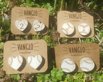 Peut inclure: Quatre paires de boucles d'oreilles en bois sur le thème du baseball sur du papier cartonné brun. Les boucles d'oreilles sont en forme de balles de baseball et de cœurs. Le texte "VANGLO creations" est imprimé sur chaque carte.