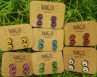 Pode incluir: Conjunto de oito pares de brincos de pressão com a forma de uma pata de animal em cartões marrons com o texto "VANGLO creations". Os brincos são de várias cores, incluindo roxo, amarelo, azul, vermelho, rosa, verde e branco.