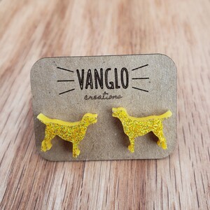 May include: A pair of yellow glitter dog silhouette earrings on a brown card with the text "VANGLO creations".