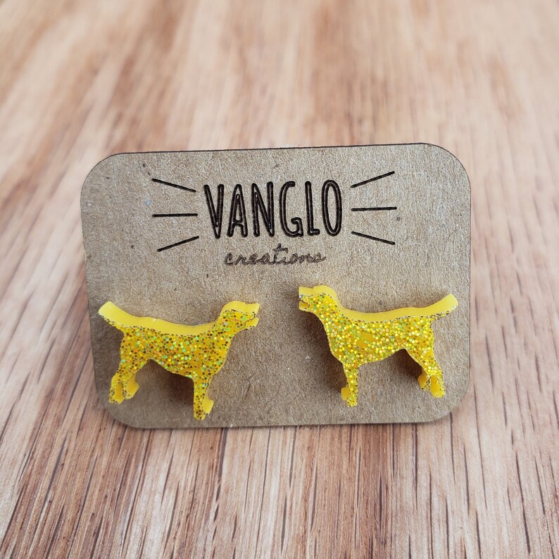 May include: A pair of yellow glitter dog silhouette earrings on a brown card with the text "VANGLO creations".