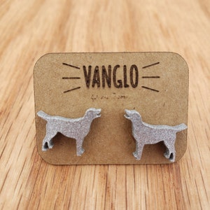 May include: A pair of silver dog-shaped earrings on a brown card with the text "VANGLO" printed on it.