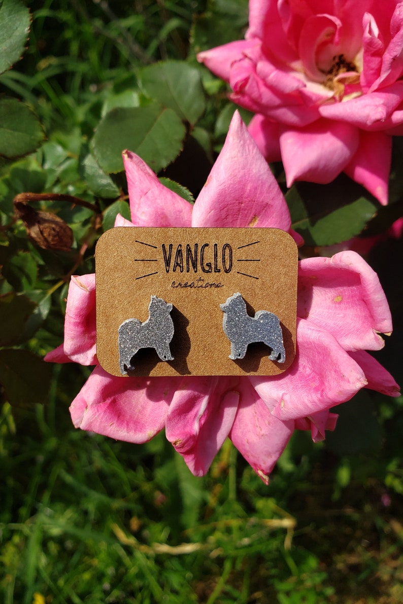 May include: A pair of silver glitter dog silhouette earrings on a brown card with the text "VANGLO creations".