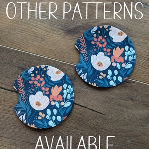 May include: Two round, dark blue and white floral patterned coasters with a cut-out for a cup. The text "OTHER PATTERNS AVAILABLE" is printed below the coasters.