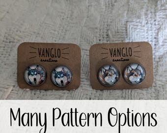 May include: Two pairs of wolf-themed earrings on display cards. The cards are brown with white text that reads "VANGLO creations".