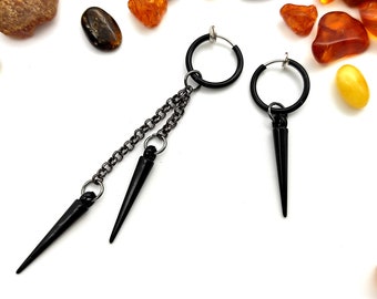 May include: A pair of black clip-on earrings with a dangling chain and two sharp, black spikes. One earring has a single spike, while the other has two spikes.