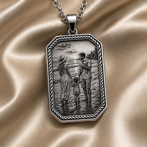 May include: A silver-toned rectangular pendant necklace featuring an engraved scene of a family of four walking on a beach. The pendant has a rope-style border and hangs from a matching silver-toned chain. The engraving depicts a sunset.