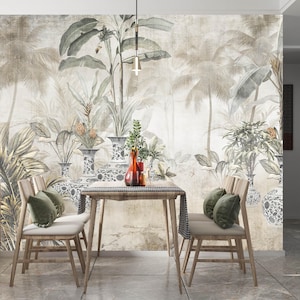 May include: A dining room scene featuring a wooden table and chairs set against a tropical-themed mural. The mural depicts palm trees and lush foliage in muted tones. Green velvet pillows adorn the chairs, and a red vase sits on the table.