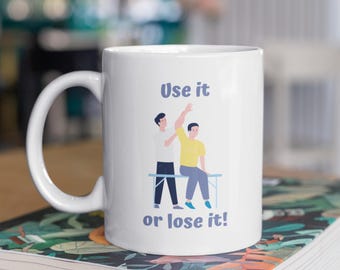May include: White ceramic mug with a blue and yellow illustration of a physical therapist working on a patient. The text on the mug reads "Use it or lose it!"