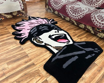 May include: A tufted rug shaped like an anime character head with spiky light pink hair, a black headband, and a wide-open mouth expression. The character has a white face, dark grey accents, and a black torso section, crafted with a textured pile.