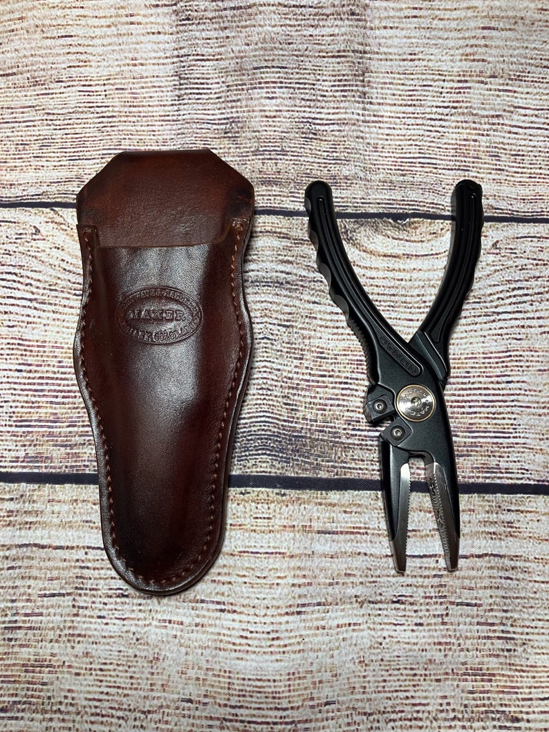 May include: A black leather sheath with a brown leather belt loop and a black multi-tool with a silver handle.