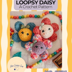 May include: Image of three crocheted flower toys in blue, red, and purple, each with a yellow or pink center and small black eyes. The text "LOOPSY DAISY A Crochet Pattern" is at the top. A rainbow bead garland and the text "NO-SEW" are also visible.