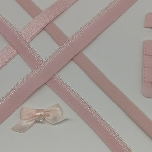 Peut inclure: Deux extensions de bretelles de soutien-gorge roses, deux jeux de fermoirs de soutien-gorge en métal, deux anneaux en métal, deux rubans de satin roses, un ruban rose avec bordure en dentelle et un nœud en satin rose avec un centre en perle.