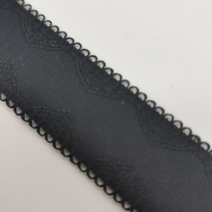 May include: Black elastic trim with a scalloped edge. The trim has a subtle textured pattern.