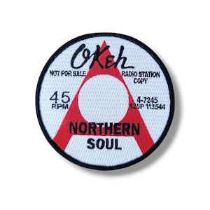 May include: Round patch with the word "Okeh" in black script above a red triangle. The patch also features the words "Northern Soul," "45 RPM," and "Radio Station Copy." The patch is white with a black border.