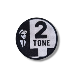 May include: A circular patch in black and white, with the text "2 TONE" and a graphic of a man in sunglasses. The number 2 is a prominent feature. This patch is likely designed for application on clothing or accessories.