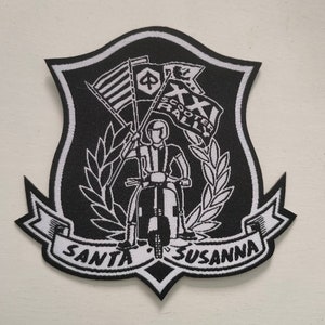 Puede incluir: Parche bordado en blanco y negro con temática de rally de scooters. Presenta a una persona conduciendo un scooter, banderas y el texto "XXI Scooter Rally Santa Susanna".