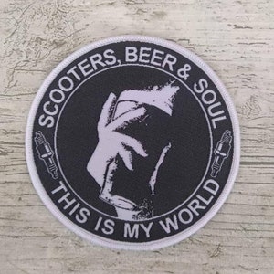 Puede incluir: Parche redondo blanco con texto negro que dice "Scooters, Beer & Soul This Is My World". El parche presenta una silueta blanca de una mano sosteniendo una jarra de cerveza.