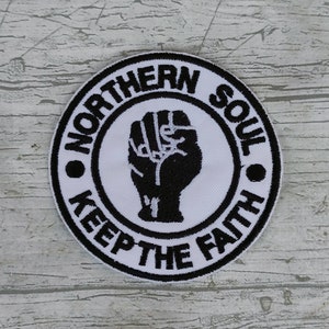 Op de afbeelding: Zwart-witte geborduurde patch met een gebalde vuist en de tekst "Northern Soul Keep The Faith".