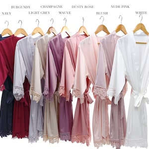 Pu&ograve; includere: Dieci accappatoi di raso in vari colori, tra cui blu navy, bordeaux, grigio chiaro, champagne, malva, rosa polvere, blush, rosa nude e bianco. Ogni accappatoio ha un bordo in pizzo e una cintura abbinata.