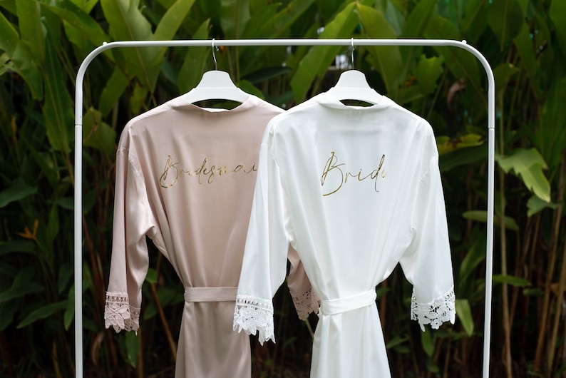 A pink robe and a white robe hanging on hangers