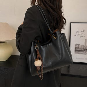 Brown leather tote bag for women featuring a spacious vintage-inspired design, double shoulder straps, magnetic closure, and decorative charm, ideal for work, commuting, travel, and everyday use.
