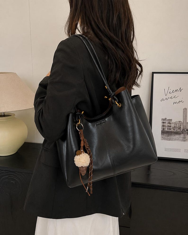 Brown leather tote bag for women featuring a spacious vintage-inspired design, double shoulder straps, magnetic closure, and decorative charm, ideal for work, commuting, travel, and everyday use.