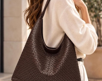 May include: A dark brown hobo bag featuring an intricate woven leather pattern across its entire surface. The bag has a single integrated shoulder strap and a slouchy, triangular silhouette with smooth leather trim along the top opening.