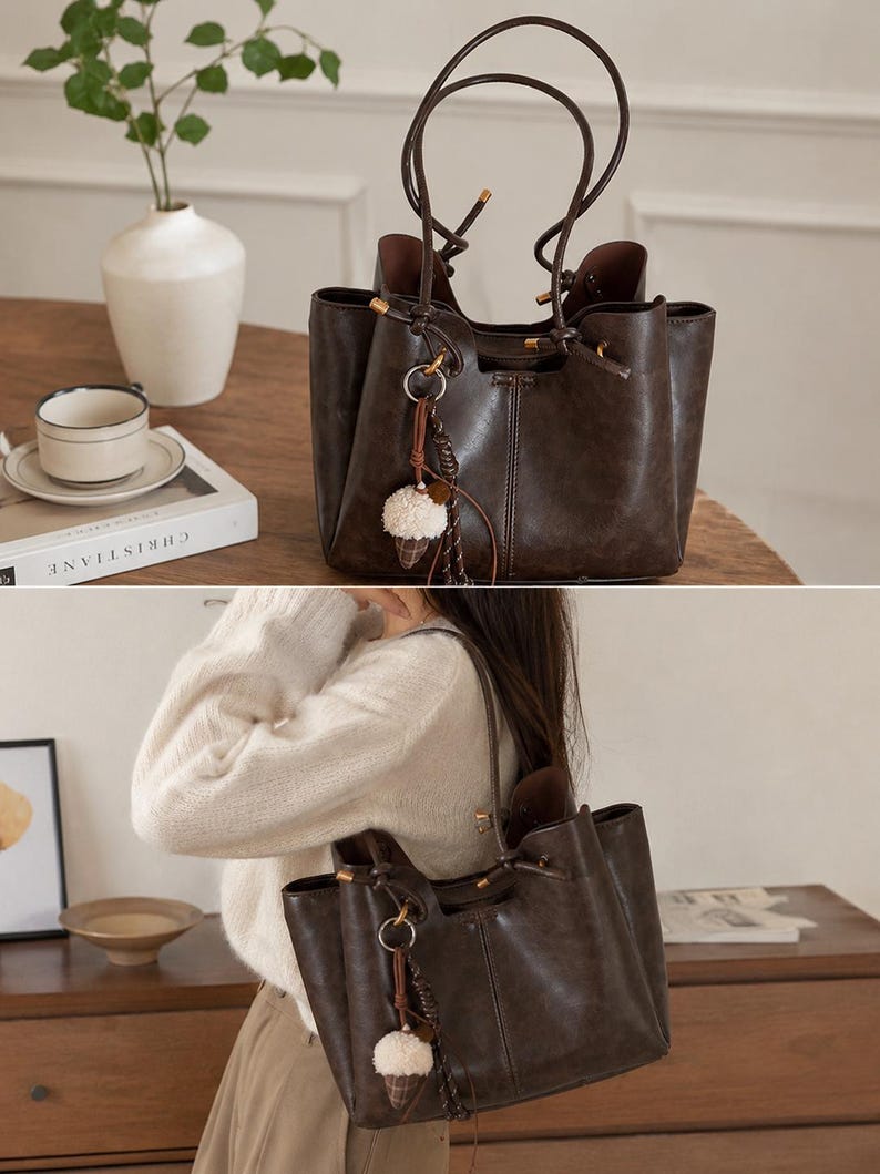 Brown leather tote bag for women featuring a spacious vintage-inspired design, double shoulder straps, magnetic closure, and decorative charm, ideal for work, commuting, travel, and everyday use.