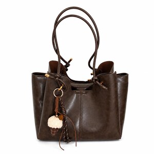 Brown leather tote bag for women featuring a spacious vintage-inspired design, double shoulder straps, magnetic closure, and decorative charm, ideal for work, commuting, travel, and everyday use.