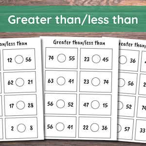 Pode incluir: Tr&ecirc;s folhas de trabalho brancas com o t&iacute;tulo "Greater than/less than". Cada folha cont&eacute;m problemas de matem&aacute;tica com n&uacute;meros e c&iacute;rculos para s&iacute;mbolos de compara&ccedil;&atilde;o. O fundo &eacute; uma superf&iacute;cie de madeira.