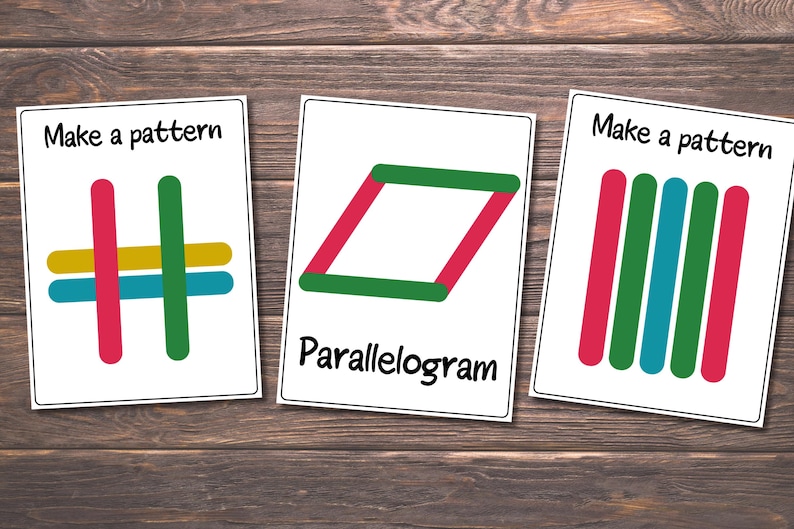 May include: Three white cards with colorful popsicle stick patterns on a wooden surface. The cards read "Make a pattern" and "Parallelogram". The patterns include red, green, blue, and yellow sticks.