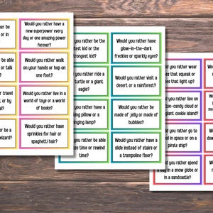 May include: Three sets of colorful cards with the text "Would you rather..." in black. Each card has a different question with a choice of two options. The cards are on a wooden surface.