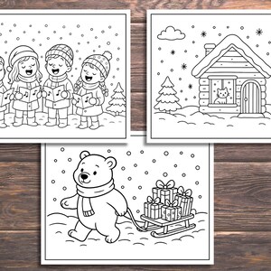 May include: Three black and white coloring pages on a wooden surface. One shows children singing carols, another a cabin with a cat in the window, and the last a bear pulling a sled of gifts. Snowflakes are falling.